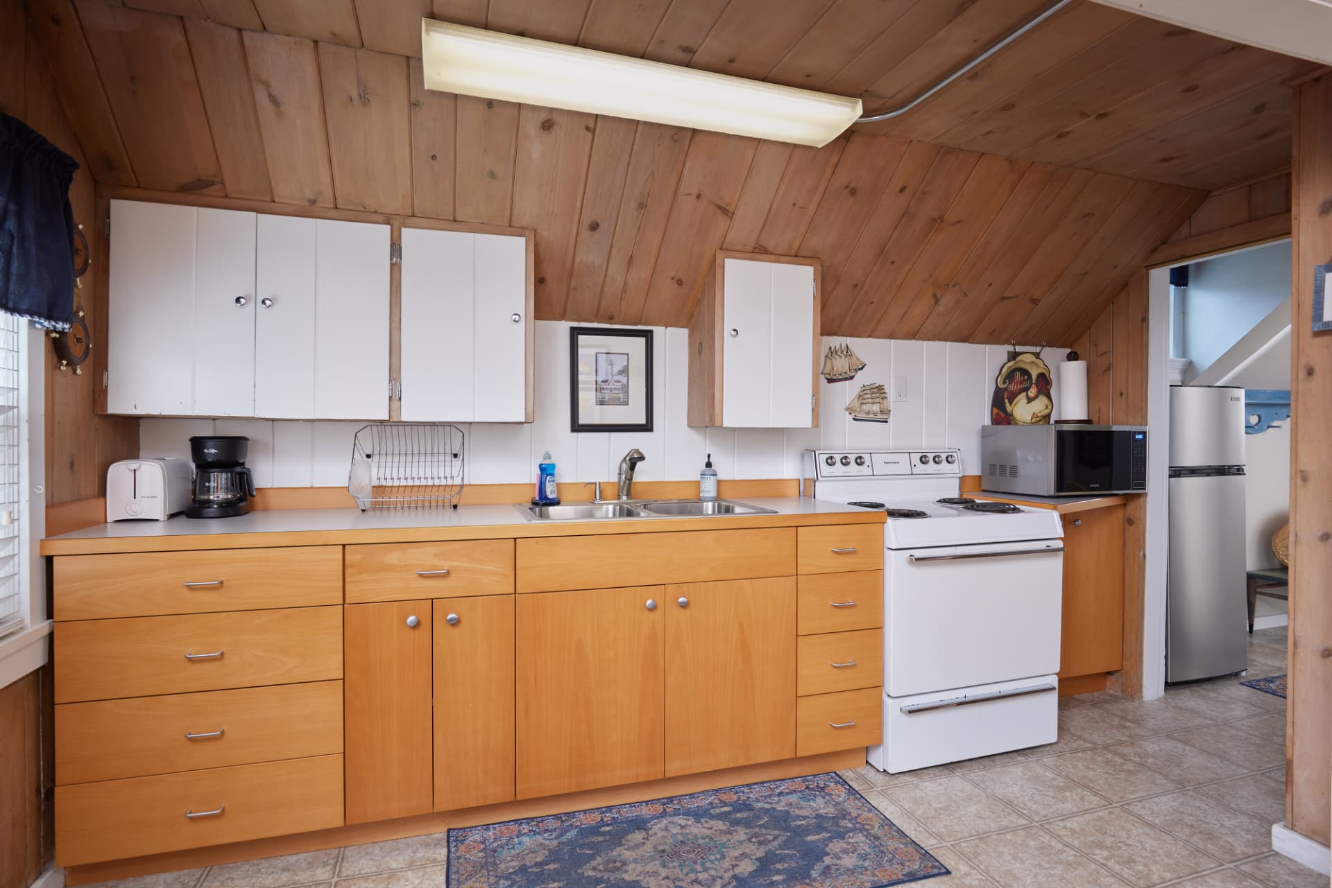 The Harbor kitchen with light wood cabinets and sloped pine ceiling