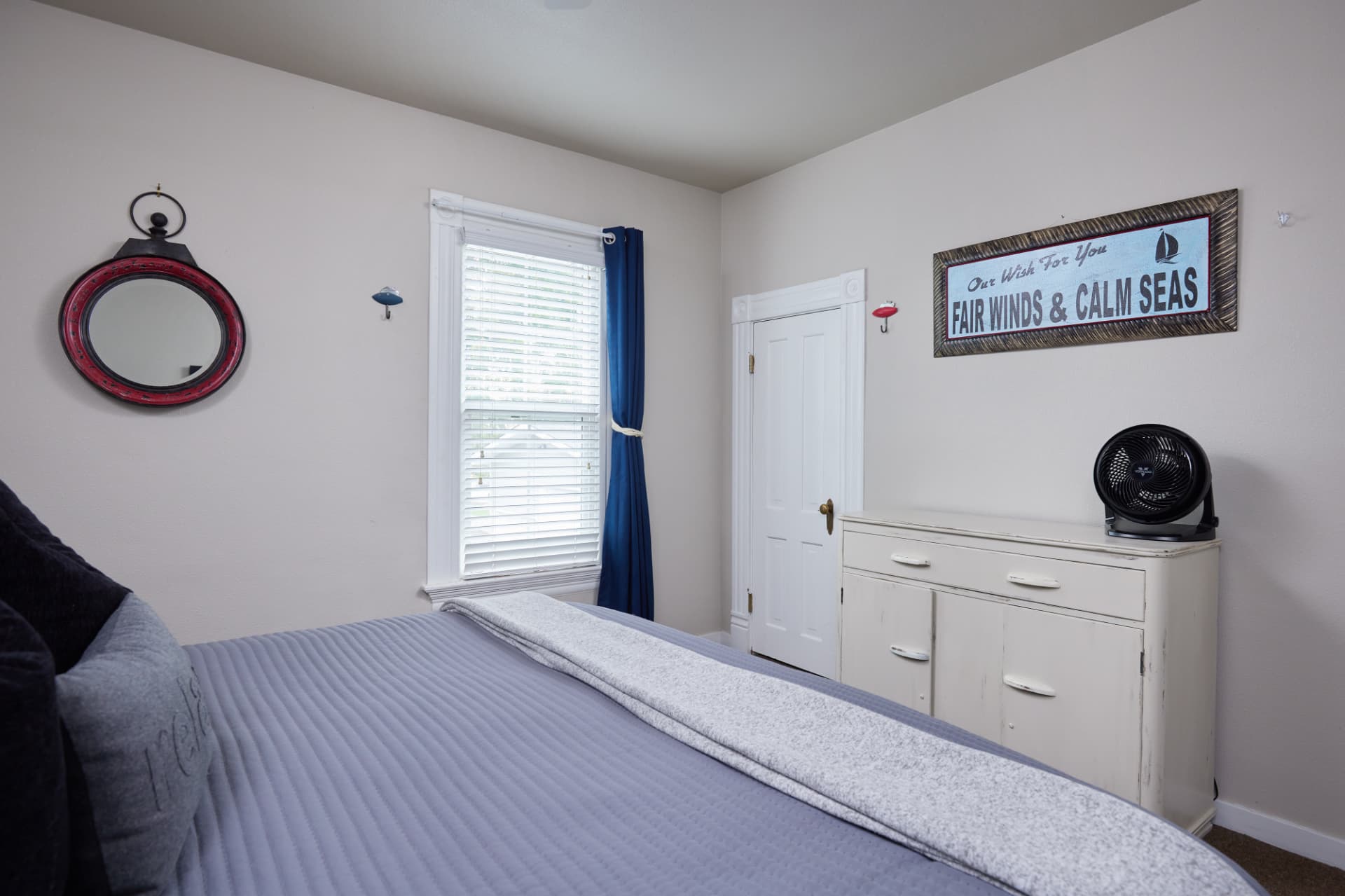 The Harbor bedroom with white dresser and maritime wall art